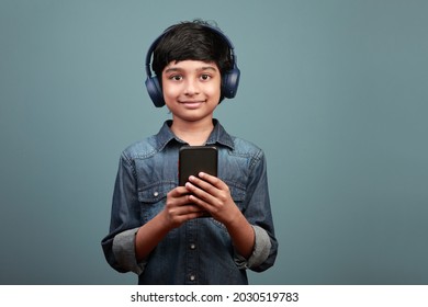 Smiling boy wearing a headset holding a smart phone in hand