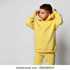 Smiling boy in a yellow tracksuit with a hood and trousers isolated on white. Portrait of a child in cool clothes puts on a hood. Kids fashion, casual wear, comfortable kids wear. - Shutterstock ID 2005684019