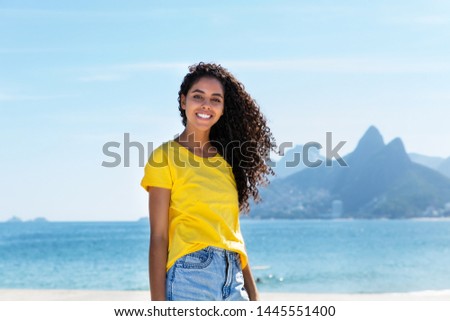 Smiling brazilian woman at Ipanema beach at Rio de Janeiro with beach and mountain in summer