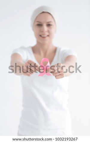 Smiling breast cancer survivor holding a pink ribbon as a symbol