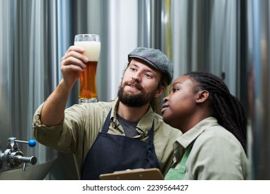 Smiling brewery workers checking thickness of beer froth - Powered by Shutterstock