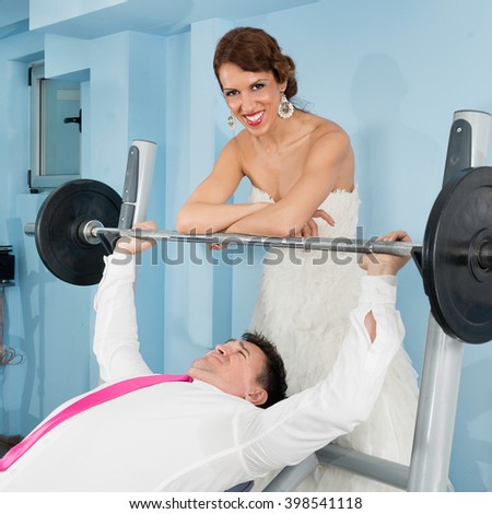 Smiling bride adding weight to a hardworking groom