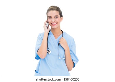 Smiling Brown Haired Nurse In Blue Scrubs Making A Phone Call On White Background