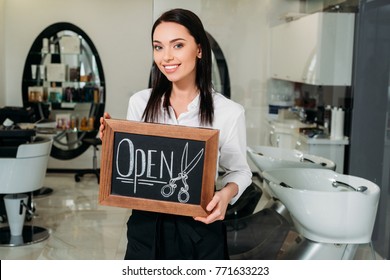 Smiling Brunette Owner Of Salon Standing With Sign Open