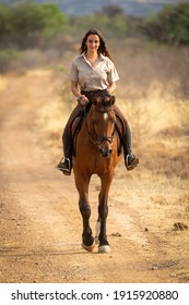 Smiling brunette rides horse along dirt track