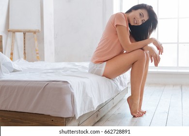Smiling brunette sitting on bed