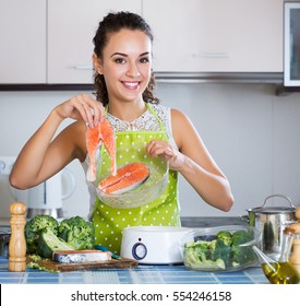 Smiling Brunette Woman Cooking Trout In Steamer For Healthy Lunch