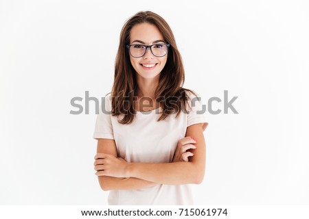 Smiling brunette woman in eyeglasses posing with crossed arms and looking at the camera over white background