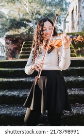 Smiling Brunette Woman Playing Violin Outside In The Woods. Vertical