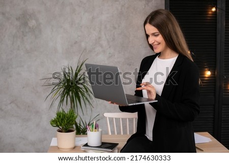 Smiling brunette woman using laptop computer over gray background. Working woman.
