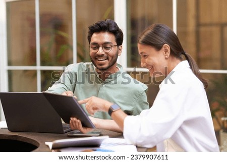 Smiling business colleagues discuss biz issue while use laptop and digital tablet in office terrace