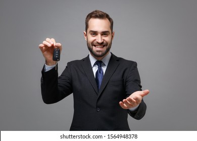 Smiling Business Man In Classic Black Suit Shirt Tie Posing Isolated On Grey Background. Achievement Career Wealth Business Concept. Mock Up Copy Space. Stand With Otstretched Hand, Holding Car Keys