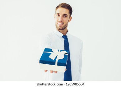 Smiling Business Man Giving Gift Box With Ribbon. Blurred Attractive Guy Looking At Camera. Gift Concept. Isolated Front View On White Background.