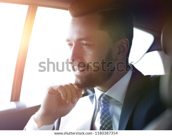 Smiling\
business man sitting in the back seat of a\
car
