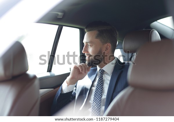 Smiling\
business man sitting in the back seat of a\
car