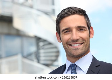 Smiling business man standing outside office building