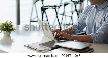 Smiling business man using laptop at office. Male hands typing on the notebook keyboard.Concept of young people work mobile devices