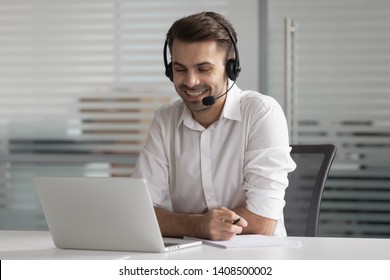 Smiling Business Man Wearing Wireless Headset Make Conference Video Call Looking At Laptop Screen, Happy Salesman Customer Service Support Agent Helpline Representative Talk By Online Chat In Office