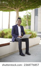 Smiling business man working on laptop at park. Young indian student or remote teacher using computer remote studying, virtual training, watching online education webinar at home office. - Shutterstock ID 2368776857