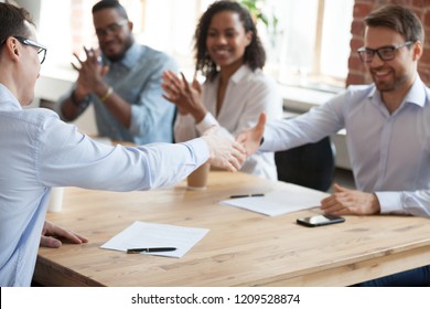 Smiling business partners shake hands after successful negotiations in office, excited male workers handshake greeting with employment, happy employees get acquainted at meeting. Partnership concept