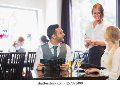 Smiling business people ordering dinner from pretty waitress