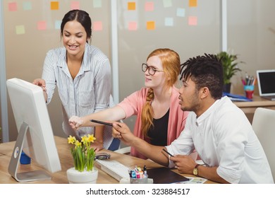 Smiling business people pointing towards computer at desk during meeting - Shutterstock ID 323884517