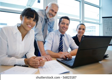 Smiling Business People Sitting At A Desk In Front Of A Laptop Computer