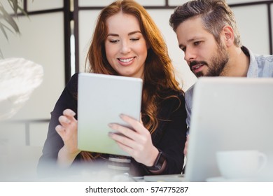 Smiling business people using laptop in creative office