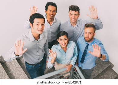 Smiling Business People Waving On Office Stairway