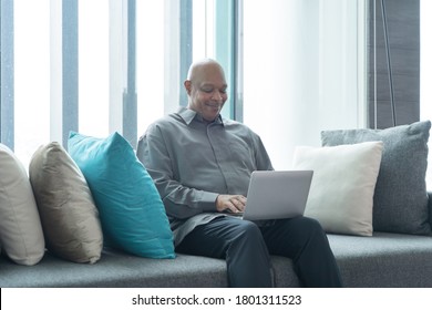 Smiling Business Senior Old Elderly Black American Man, African Person Working From Home On Table With Computer Notebook Laptop In Quarantine In Corona Virus Pandemic Concept.