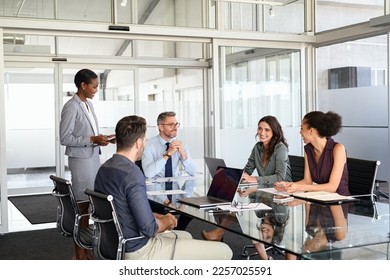 Smiling business team discussing work in meeting using laptop and documents in conference room. Successful business woman and businessmen discussing marketing strategy and ideas at meeting room.  - Powered by Shutterstock