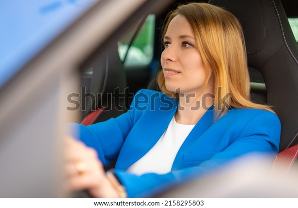 Smiling\
business woman driving a car in the blue\
suit