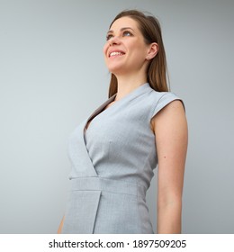 Smiling business woman in gray dress posing on gray background and looking away.
