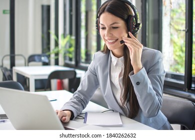 Smiling business woman with headset using laptop in office - Shutterstock ID 1840262632