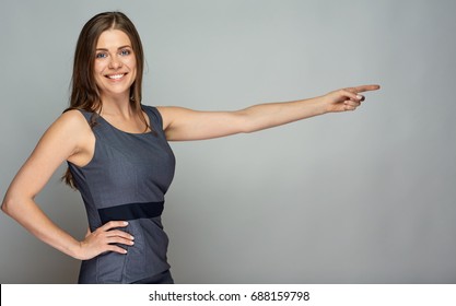 Smiling business woman pointing finger at gray copy space background. - Shutterstock ID 688159798