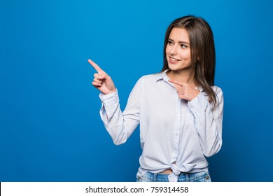 Smiling business woman pointing finger at copy space. White shirt. Long hair. Blue wall.
