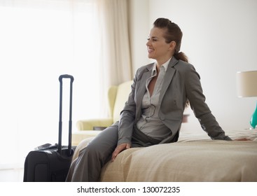 Smiling Business Woman Sitting On Bed In Hotel Room