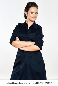 Smiling business woman standing against isolated gray background. Female model in black dress.