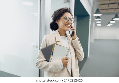 Smiling business woman standing in office background and talking by phone with colleague - Powered by Shutterstock