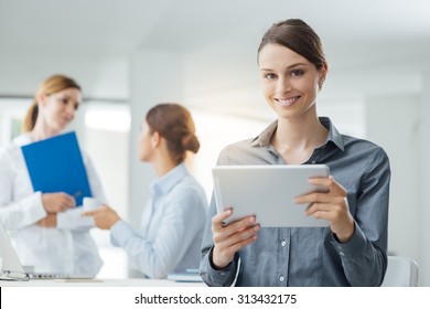 Smiling Business Woman Using A Digital Tablet And Female Office Workers Talking On Background