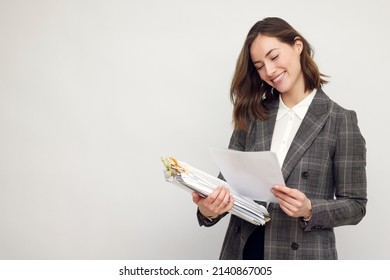 Smiling business woman with work in hands, standing isolated on white, looking happy about the papers she's reading and holding. - Powered by Shutterstock