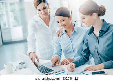 Smiling business women team working at office desk and discussing a project on a laptop