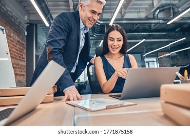 Smiling businessman and businesswoman using laptop and talking about work process - Shutterstock ID 1771875158