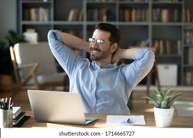 Smiling businessman freelancer wearing glasses leaning back in chair with hands behind head, happy satisfied young man dreaming about good future, new opportunities, visualizing success