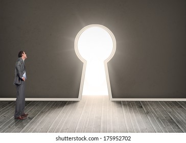 Smiling businessman with hands on hips against door revealing bright light - Shutterstock ID 175952702