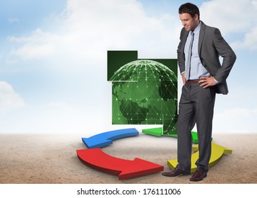 Smiling businessman with hands on hips against colorful arrows in a desert landscape - Powered by Shutterstock