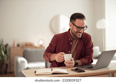 Smiling businessman having an online meeting, holding a cup of coffee. - Powered by Shutterstock