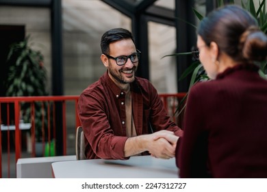Smiling businessman looking at the female colleague, shaking hands. - Shutterstock ID 2247312727