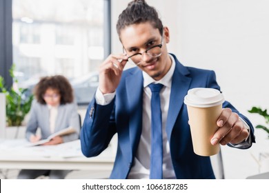 Smiling businessman offering coffee in paper cup - Powered by Shutterstock