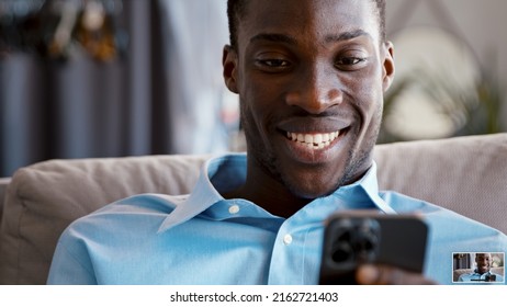 Lächelnder Geschäftsmann, der Nachrichten über Smartphone auf dem Sofa zu Hause sendet